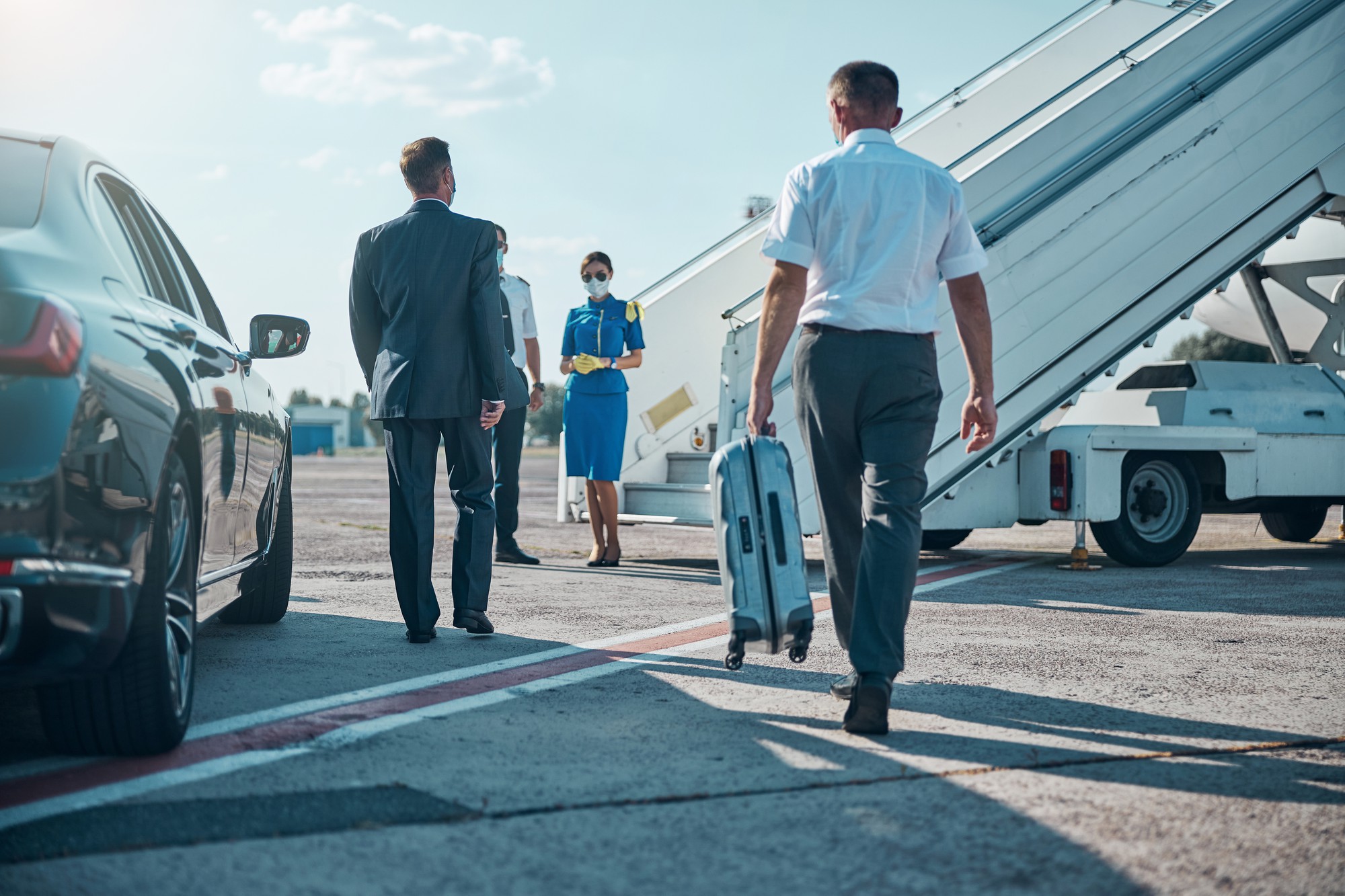 chauffeur-is-carrying-boss-luggage-while-walking-with-him-from-car-plane-pandemic